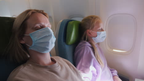 a woman with a child fly on an airplane, they are wearing protective masks. tired of the tegel flight