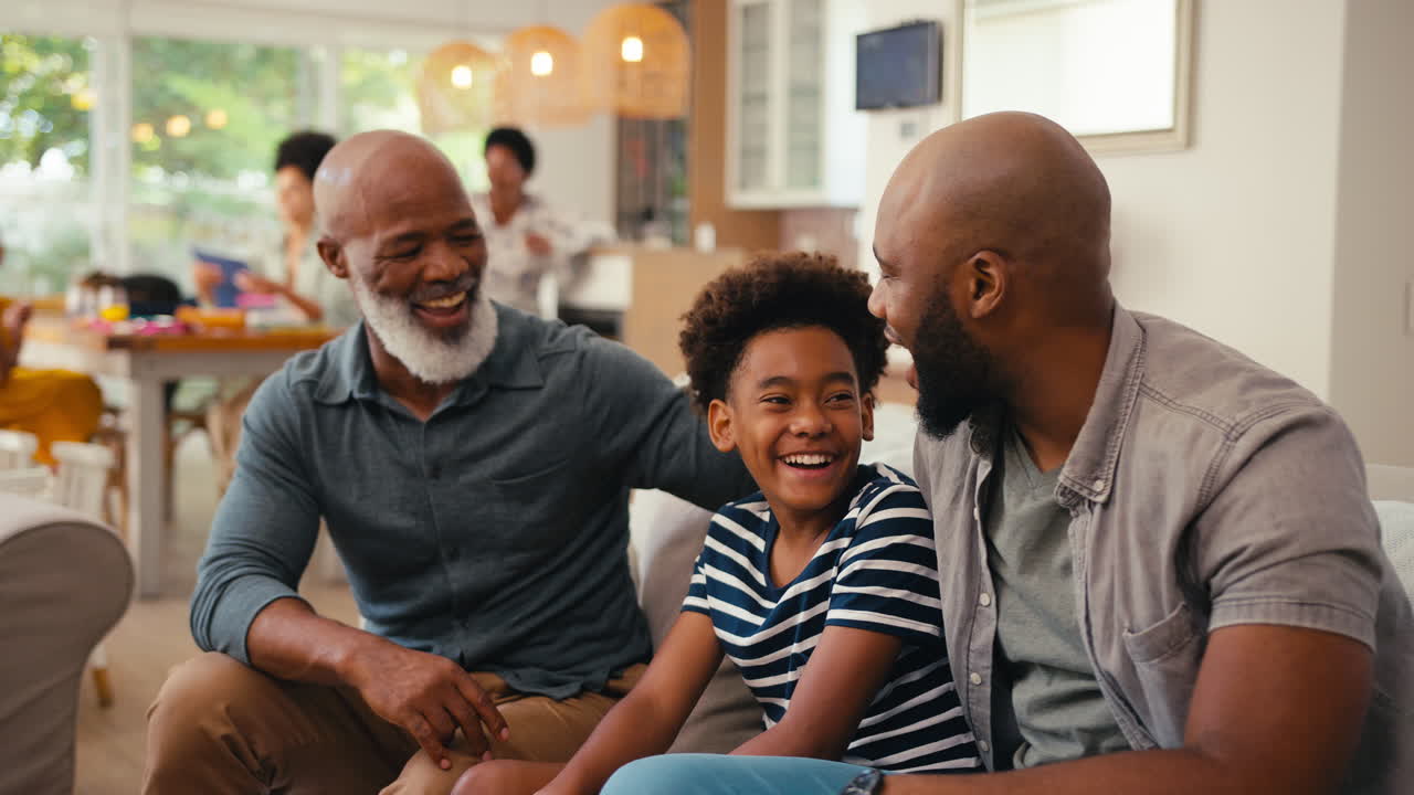 Grinende multigenerations mandefamilie hygger sig på sofaen derhjemme og snakker sammen