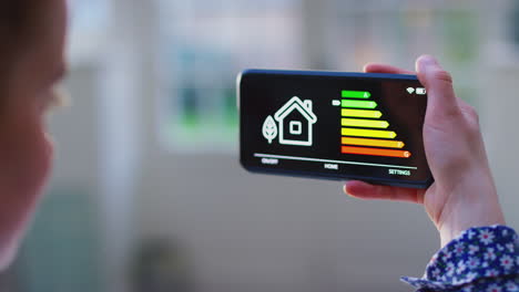 close up of woman with app on mobile phone to measure household energy efficiency at home - shot in slow motion