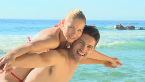 cute couple pretending to fly on a beach