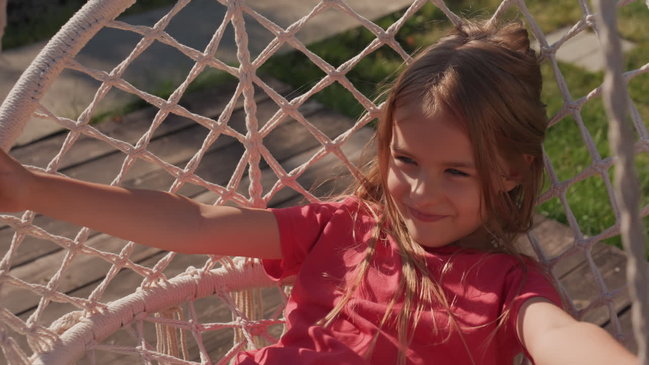 Young Girl Happily Swinging Outdoors In Sunlight, Woman Joyful Swinging In Bright Yard During Breezy Day, Young Woman Delights In Swinging In Sunlit Yard Amid Breezy Environment And Cheerful Mood