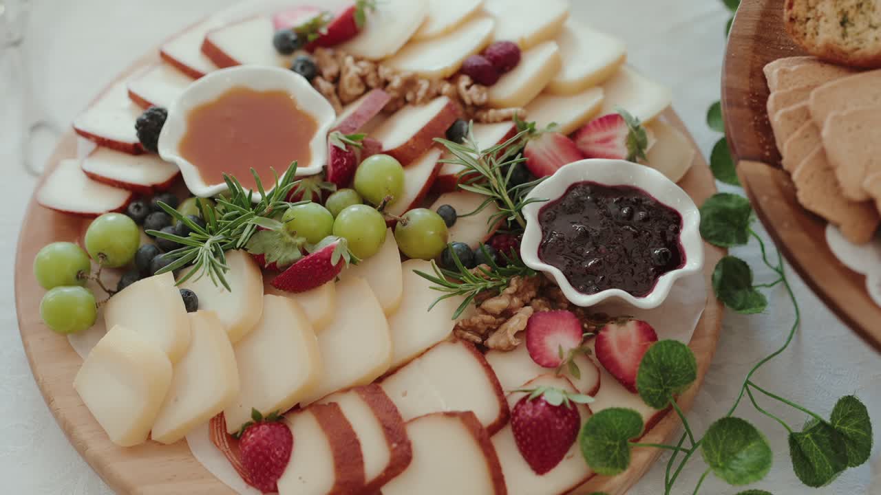 Sliced cheese with grapes strawberries jam honey and walnuts on a wooden board for serving