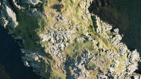 Top-down-island-reveal-in-dark-water-with-sparkling-sunshine-at-Wastwater-Lake-District-UK