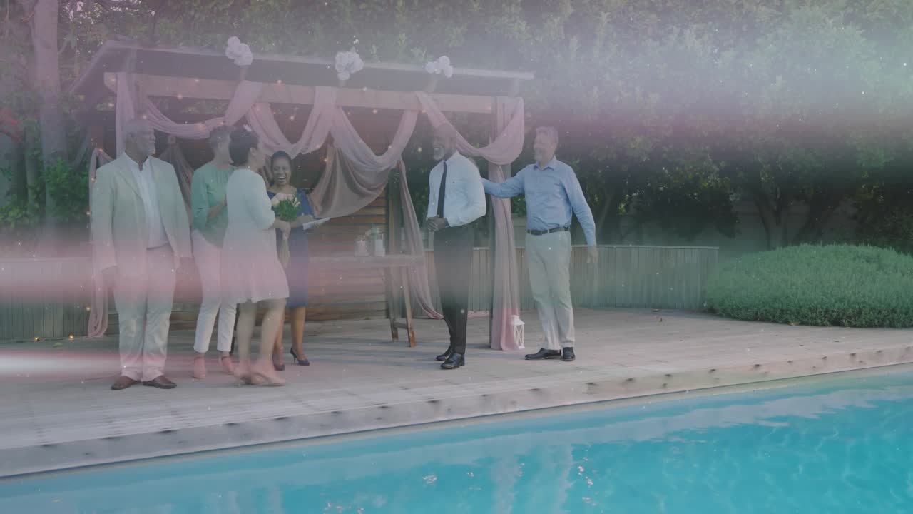 Poolside wedding group, bride entering left, light bands streaking, group closing for recognition