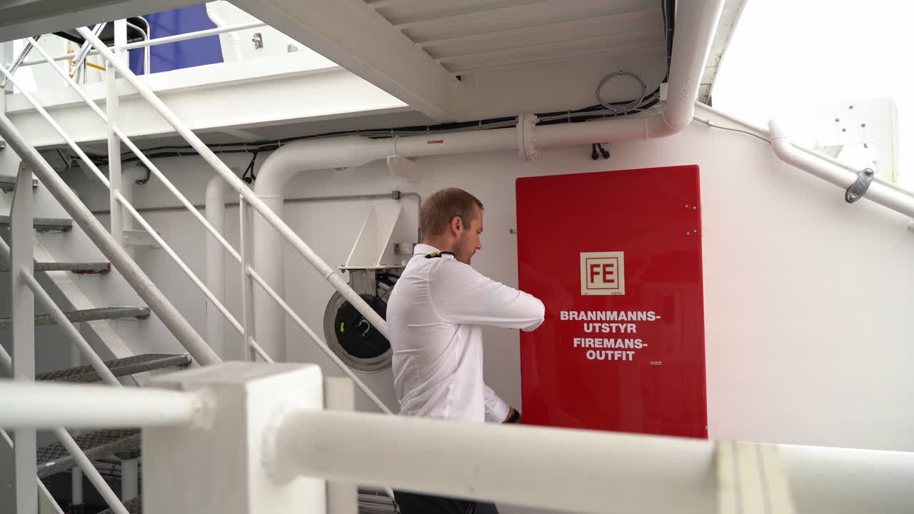 капитан судна проверяет противопожарное и коптильное оборудование на судне - закрывает шкаф после завершения работы