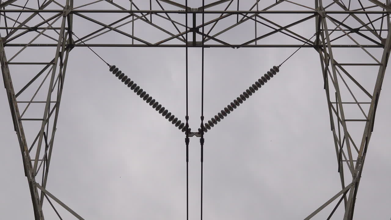 primer plano de aisladores eléctricos y estructura de torre de pilón eléctrico