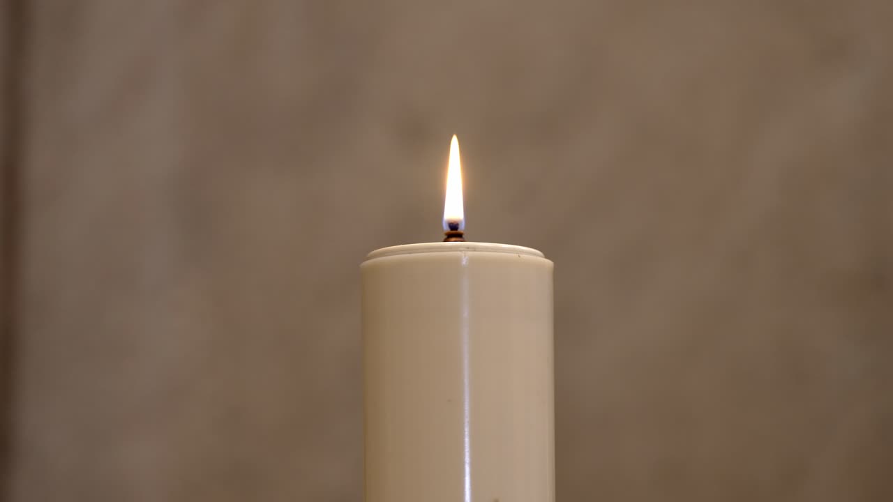 single lit candle with a calm flame against a neutral background