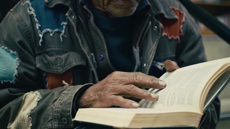 an elderly man engaged in reading a book while holding it with care, capturing the depth of his expression and the intimacy of the moment amidst a quiet setting
