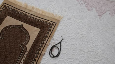 prayer rug and rosary stands next to it, islamic figures,