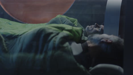 men sleeping in a sleeping bag in a capsule
