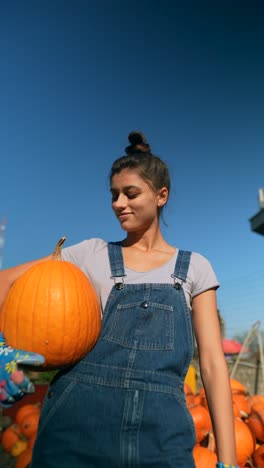 mujer joven sosteniendo una calabaza en una granja