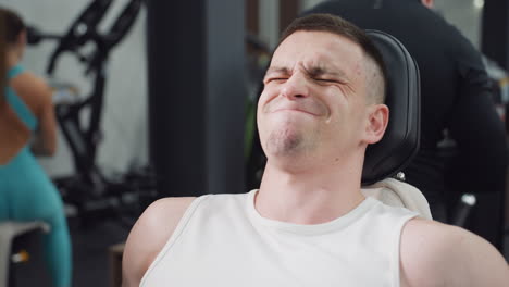 athlete facial strain working out on leg press machine demonstrating focused power and controlled motion under intense gym lighting. tense calves and quads drive strength endurance