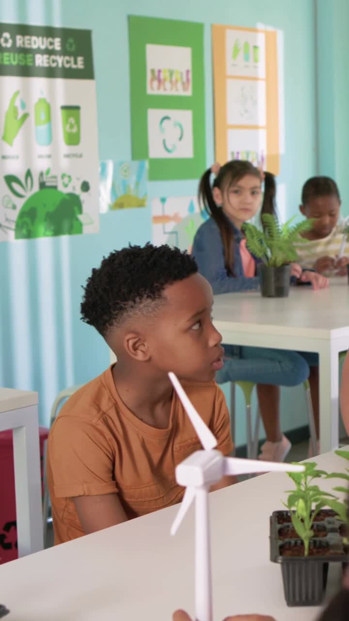 Vertical video: Teacher placing turbine, pointing, boy watching spin in class learning, copy space