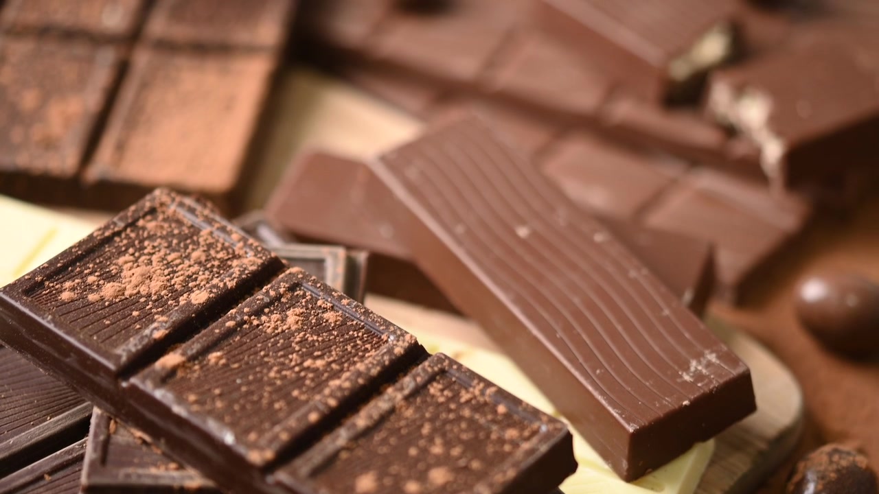 Aneka Batangan Cokelat Hitam dan Susu di atas Papan Kayu.