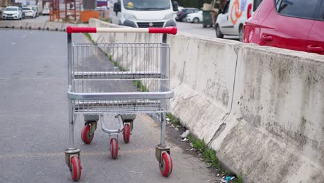 abandoned shopping cart by concrete barrier in parking lot