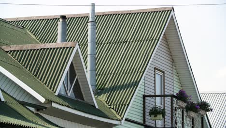 green metal roof on a light colored house with a small balcony