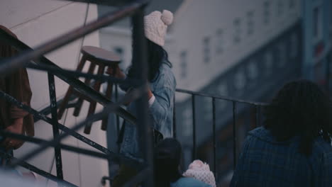 group of young multiracial friends walking up fire escape stairs ready for rooftop party chatting sharing excitement for weekend celebration