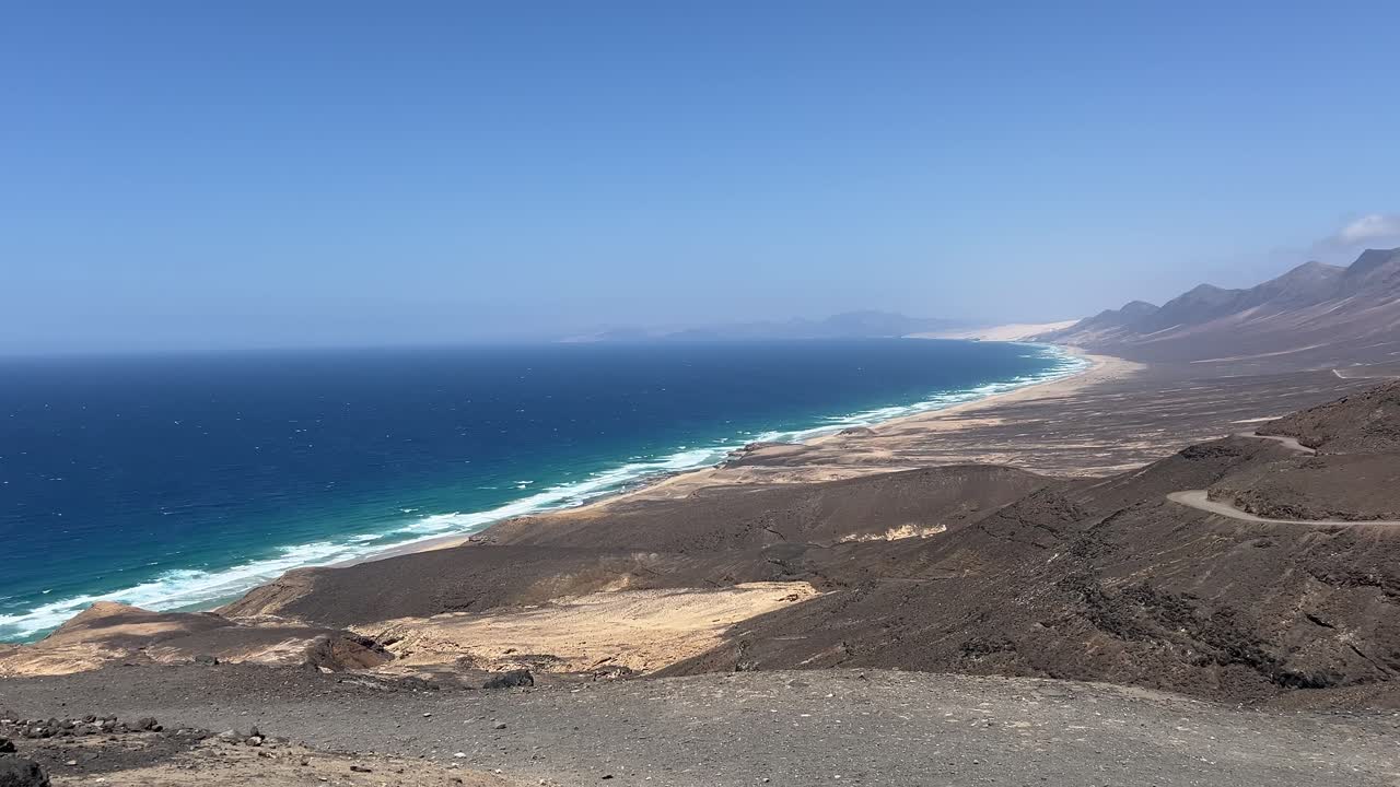 Breathtaking high-angle view of the remote and wild Cofete Beach, with turquoise Atlantic waves crashing on the vast sandy shore. Jandia, Fuerteventura, Spain