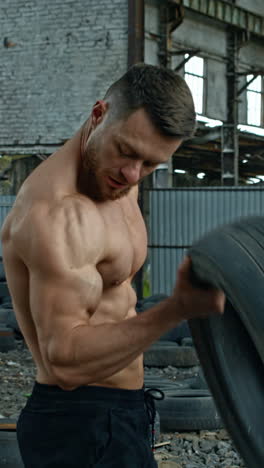man training with tire. muscular fitness man training with old tire wheel