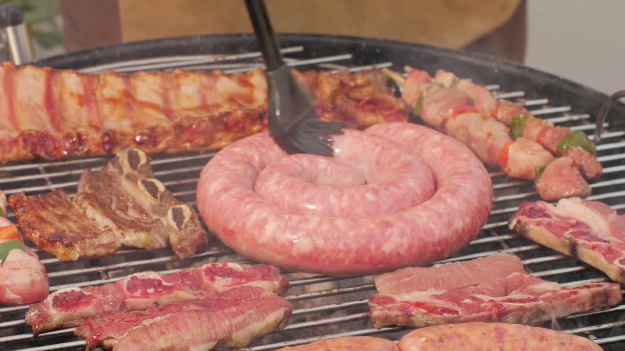Traditional spanish barbeque, big sausage chorizo botifarra, pork and beef ribs on grill with fire, american style cooking, chef grilling meat fat food, steaks and sausages on bbq. High quality 4k footage