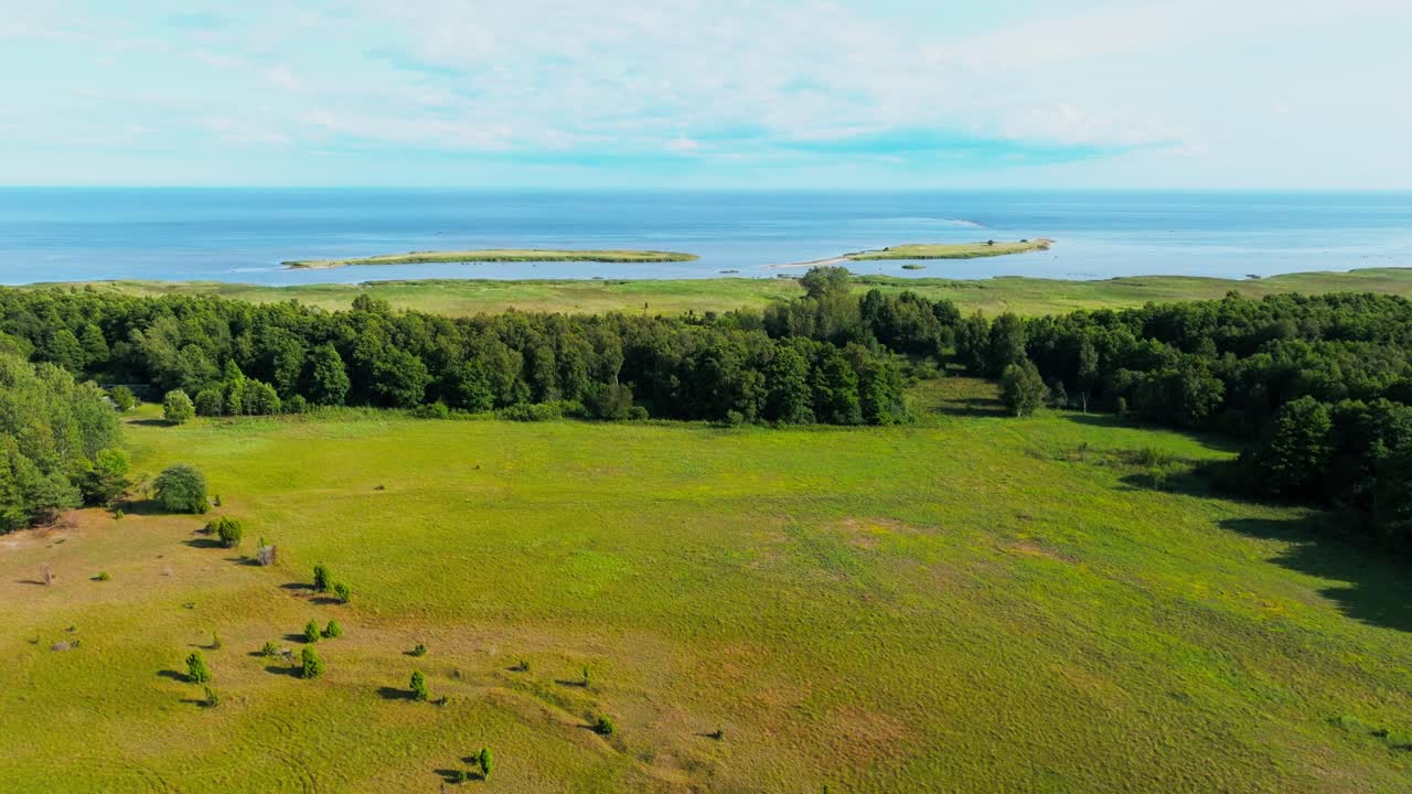Flying over coastal countryside with trees and fields, towards islands in the sea