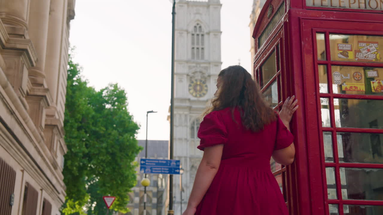 Woman Standing By The Telephone Booth With Westminster Abbey In The Background In London, England, UK
