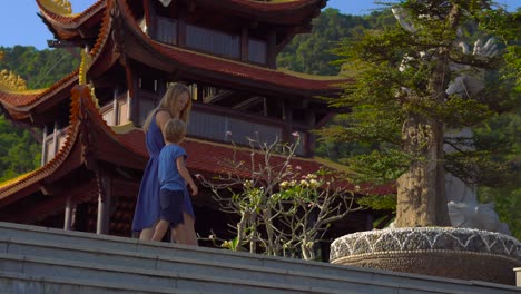 steadycam shot of a young woman and her son visiting a budhist temple ho quoc pagoda on phu quoc island, vietnam