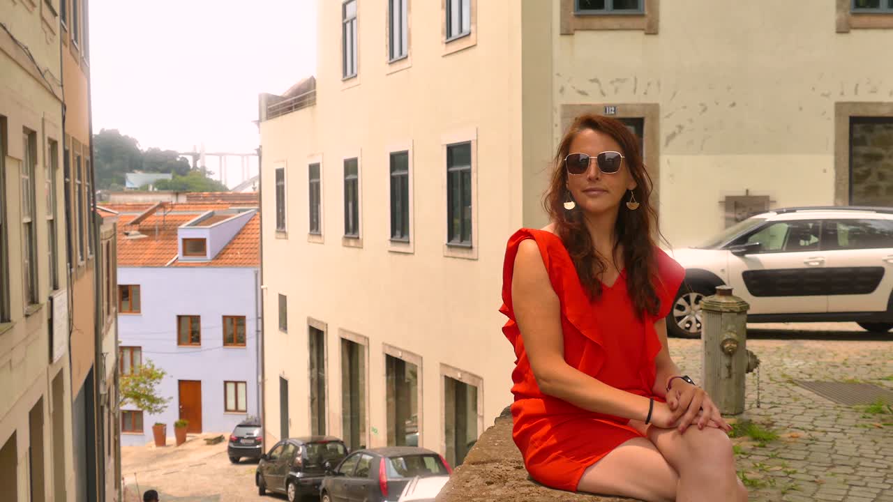 Kaunis matkailija punaisissa vaatteissa ja aurinkolaseissa Porton vanhassakaupungissa, Portugalissa