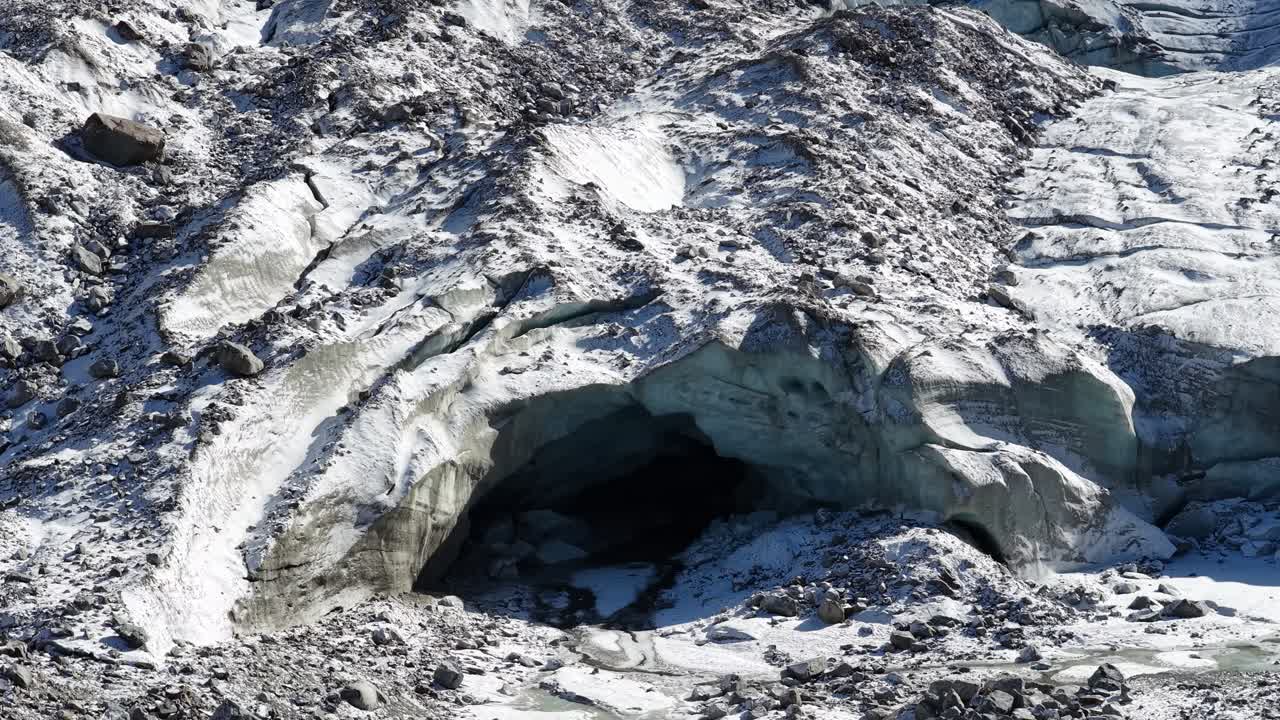 Drone close-up of glacier cave entrance with icy textures in Engadin, Switzerland