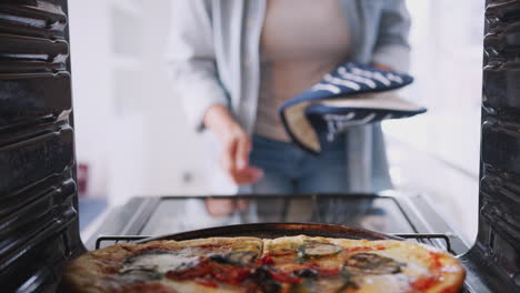 Vista-Desde-El-Interior-Del-Horno-Mientras-Una-Mujer-Cocina-Pizza-Fresca