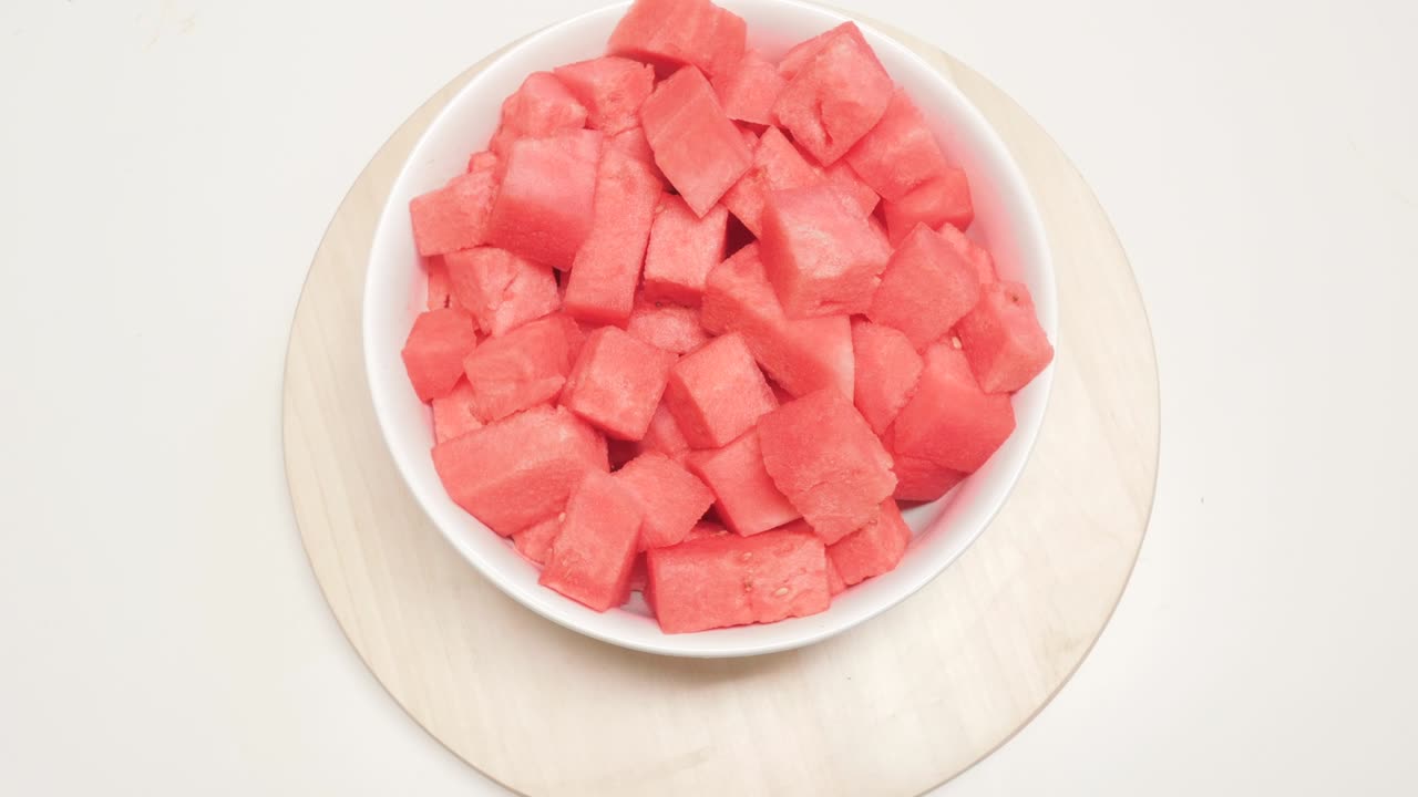 trozos de sandía en un cuenco de cerámica girando en una mesa giratoria de madera