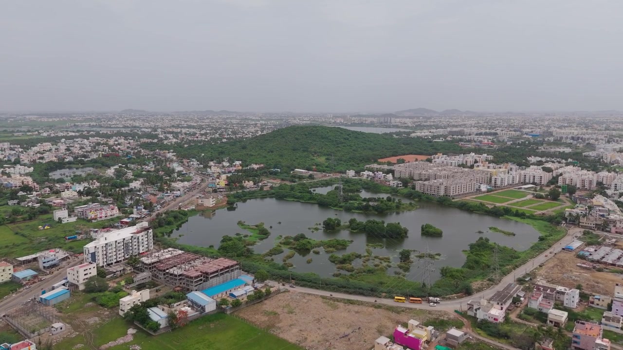 Appezzamenti residenziali si estendono vicino a un lago mentre il drone avanza verso la collina di Chennai.