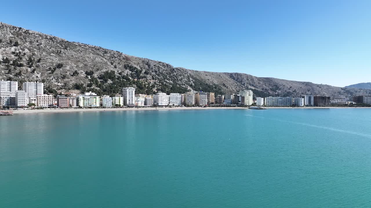 Aerial dolly on ocean to beautiful coastal town with amazing mountains