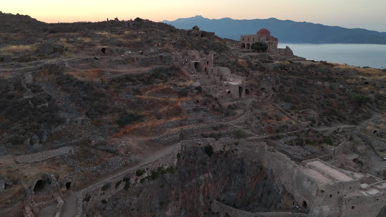 Peloponneso, Monemvasia, vista aerea dall'alto che indietreggia dalla chiesa di Hagia Sofia verso le scale che conducono alla città alta durante il tramonto. Nessuna persona. Solo rovine e natura