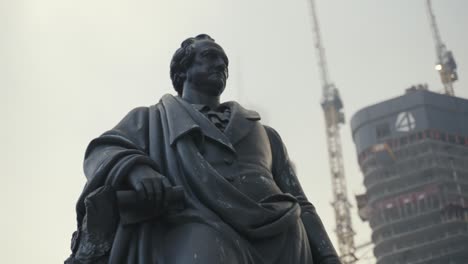 primo piano della statua di goethe con la torre quattro grattacielo sullo sfondo a francoforte in germania in una nebbiosa fredda giornata invernale mentre a goethe platz mentre la torre è in costruzione