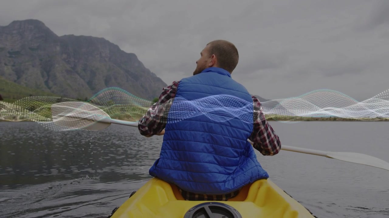 Uomo che inizia a pagaiare in kayak verso la riva montuosa, con un'onda che attraversa a metà mentre la mano sfiora l'acqua per svago
