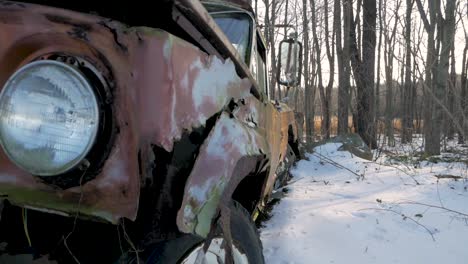 frente a un viejo auto oxidado desgastado y en descomposición en un bosque nevado