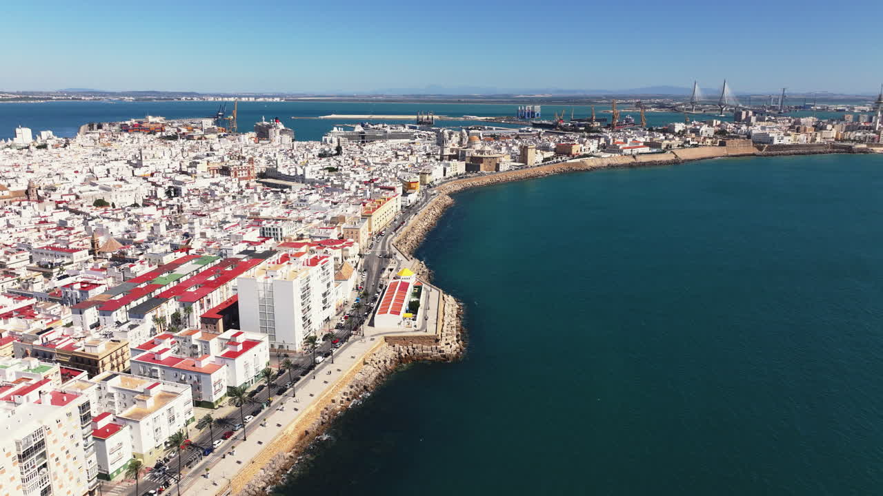 Panorama aereo da drone della costa di Cadice e del paesaggio urbano storico che si snoda lungo l'Oceano Atlantico, edifici bianchi del centro storico, lungomare in una luminosa giornata di sole in Andalusia, Spagna. Correzione colore cinematografica