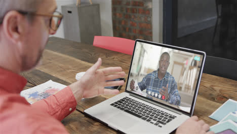 Caucasian-businessman-on-laptop-video-call-with-african-american-male-colleague-on-screen