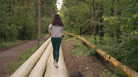 young woman walking through the forest on a path with pipes