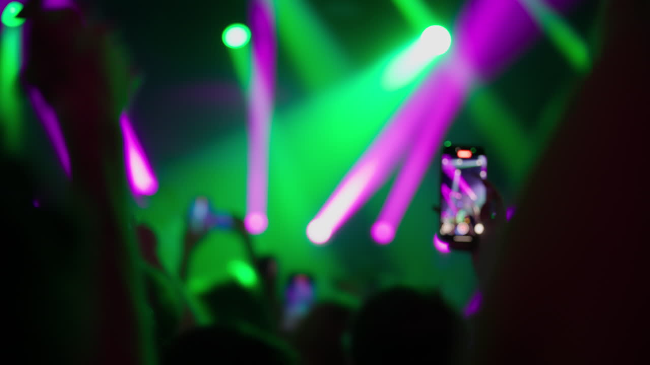 Gravação de concerto com smartphones e luzes coloridas de uma multidão animada