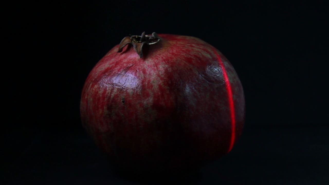 Rødt laserlys scanner granatæblefrugten i mørket