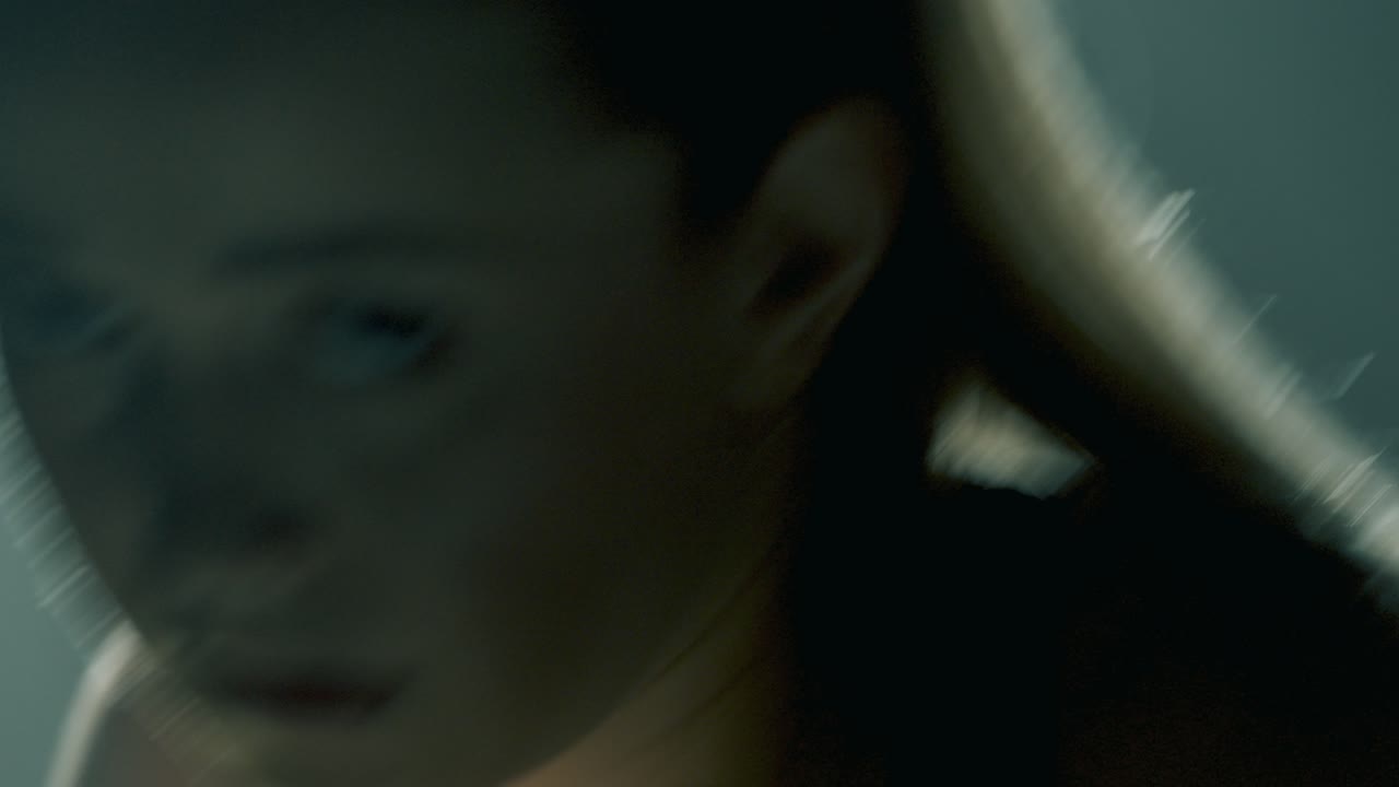 Blonde athletic woman in pink shorts and black sports bra shadow boxes toward the camera, holding yellow dumbbells. Backlight highlights her arms and hair in a smoky, cinematic training studio