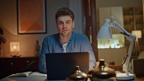 portrait smiling worker posing at night home table closeup. guy working laptop