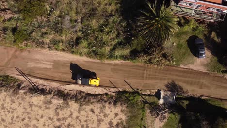 Drone-top-view-of-roller-preparing-new-build-road-in-town-during-sunny-day