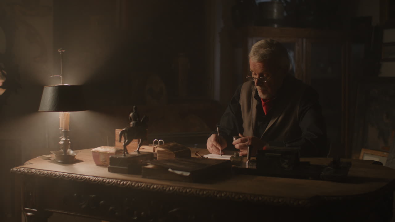 Older passionate man evaluates an old silver skull watch in his office at night