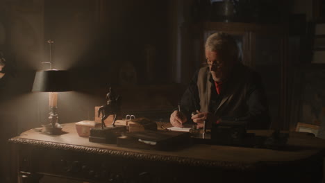 older passionate man evaluates an old silver skull watch in his office at night