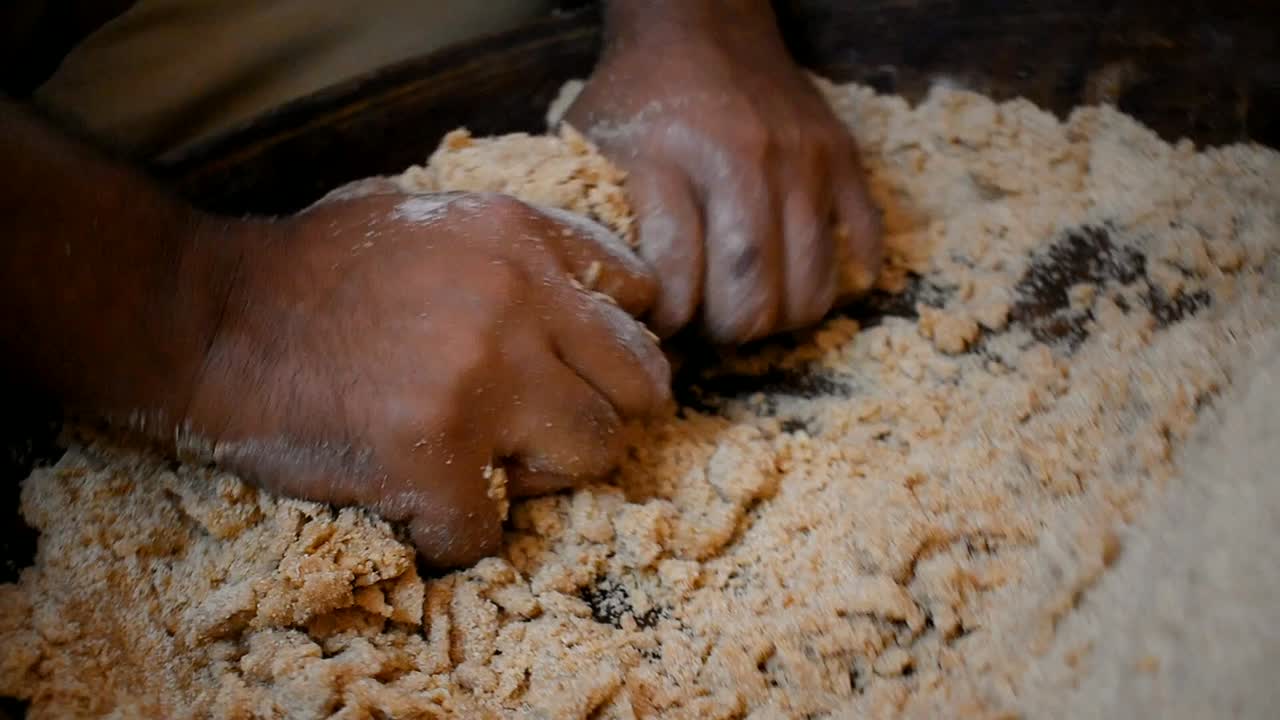 close of pair of hand rolling and kneading dough in a wooden tray.