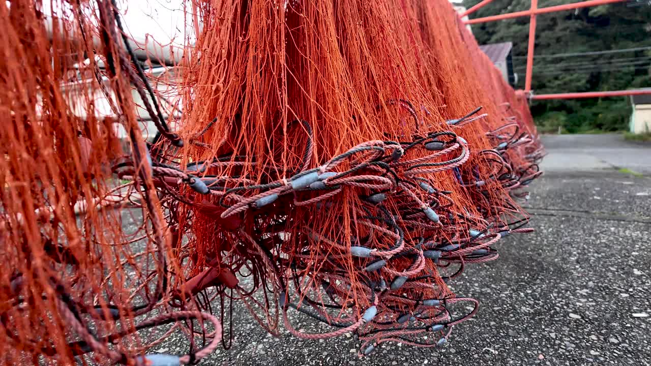 Close up of hanging red fishing nets with lead weights, drying in the sun after a fishing trip