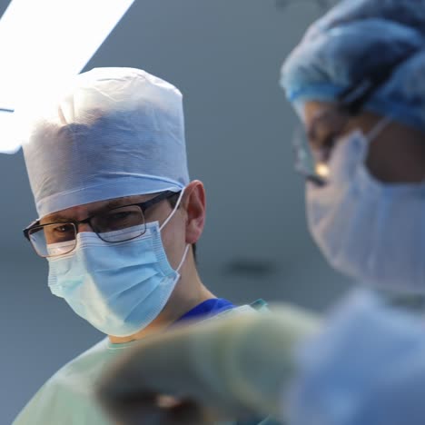 medical staff perform an operation. doctors men and female assistant in medical masks in the operating room. slow motion. healthcare concept